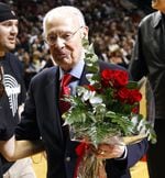 Portland Trail Blazers founding broadcaster Bill Schonely walks off the court with roses.