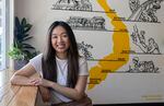 Kim Dam, the owner of Portland Ca Phe, sits in front of a painting of Vietnam in her coffee shop.