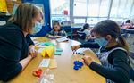 a teacher watches as a young girls sorts blue figurines while learning to count