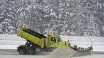 A snowplow pushes snow off a road.