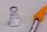A vial of Pfizer vaccine and syringe.