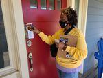 A CROWN Act campaign leader sticks a "Know Your Rights" guide in a door during  a canvassing event in Portland on Oct. 30, 2021.