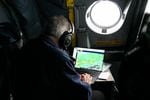 A scientist sits in the cockpit and helps coordinate a flight plan through "snow bands" in the storm.