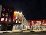The mural "Together We Bloom" by artist Michelle Angela Ortiz is illuminated by the lights from Las Adelitas, an affordable housing project in northeast Portland.
