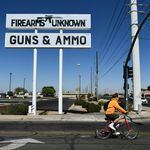 The silhouette AR-15-style rifle is displayed on signage for the Firearms Unknown Guns & Ammo gun store in Yuma, Ariz., last week.