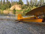 A small yellow plane on a gravel road. Not moving