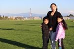 Wendi Suni Yah Canul poses with her children Mario Valle Yah (6) and Kiara Edila Valle Yah (8) with the Owens-Brockway glass recycling facility in the background in Northeast Portland's Cully Park on Oct. 7, 2021.