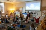 Kindergarteners in Kate Tibbitts' classroom take a "brain break," stretching before a lesson.
