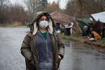 Jamie Spinelli stands bundled up in warm clothes and a mask, in front of a few tents at a homeless camp in Clark County. The weather is rainy.