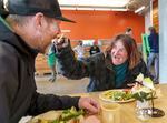 Rob Davis, left, takes a bite of food offered by Melody Rose on May 2, 2022, as Blanchet House reopened for indoor dining following more than two years of closure due to the pandemic.