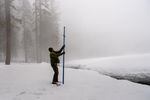 Eric Meyer uses a hollow pole thrust into the ground to measure the snow in Sequoia National Park in Round Meadow.