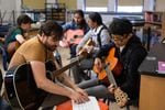 Wilson Vediner, left, teaches a student chords on the guitar at the Pass the Mic workshop at Hosford Middle School in Portland, Ore., Monday, July 29, 2019. Vediner, who's played in bands like Months and Point Juncture, WA, is the workshop's program director.