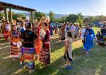 Groups of Nez Perce tribal members and descendants gather in circles to talk in some grass.