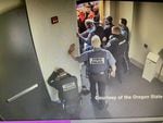 A screen capture from a video shows people in law-enforcement uniforms attempting to guard a door as a crowd surges against them and tries to gain entry