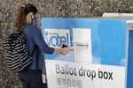 A person drops off a ballot for Washington state's primary election, Tuesday, Aug. 4, 2020, at a collection box at the King County Administration Building in Seattle. Voters in the state have the option of voting by mail, depositing ballots in boxes, or seeking help in person for a missing ballot or other issues.