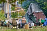 A man sits outside his camp this September in Southwest Portland. With an unexpected budget surplus, the city council has committed $18.8 million to homeless services as part of a city-county agreement on homelessness.