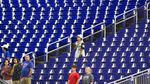 A few baseball fans stand during the singing of the National Anthem before the start of a baseball game between the Miami Marlins and the Texas Rangers, Thursday, July 21, 2022, in Miami.