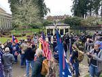 Pro-Trump supporters and riot-clad officers gather at the gates to the governor's residence in Olympia on January 6, 2021. This photograph was taken following a security breach during which a large crowd pushed through a gate and swarmed the lawn of the residence. Gov. Jay Inslee on Thursday cited that incident and the attack on the U.S. Capitol that same day as evidence that democracy is under attack in the United States. 