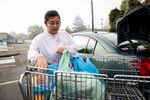 A person loads their car with a donation from a food bank.