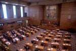 The floor of the Oregon House of Representatives shows desks aligned in rows facing other desks and a podium.