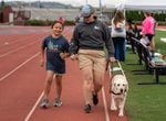 Camp Spark program manager Kirsten French and guide dog Knightley run with tether alongside camper Tianna.