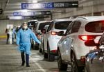 Medical assistant Melissa Morisette walks along the aisle of cars waiting at OHSU's drive-through COVID-19 testing site at the Oregon Convention Center, November 20, 2020, in Portland, Ore. COVID-19 has strained Oregon hospitals, which could see further under Gov. Kate Brown's budget proposal.