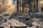 Kelly Howard looks at the remnants of a house after the Echo Mountain Complex Fire.
