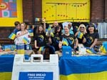 Evghenia Sincariuc, (third from right, front row) stands with members of the nonprofit organization Ukraine Care, in front of the KEEN Garage, July 7, 2022, as part of the "First Thursday in the Pearl District" event.  Ukraine Care is a nonprofit organization dedicated to providing fresh bread for people in Ukraine.