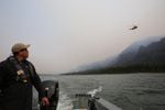 Ed Chin with All About Adventure Excursions watches as a helicopter drops a hose into the Columbia to douse hot spots at the Eagle Creek fire.