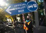 Election worker Maud Whalen holds a sign to direct drivers to the ballot box outside of the Multnomah County election office in Portland, Ore., November 2, 2020. Kristyna Wentz-Graff / OPB