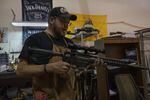 Jon Bush, a gunsmith in Vancouver, WA, holds his AR-15 in his shop. Bush says the AR-15’s popularity has largely to do with the rifle’s appearance. 