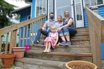 Rebecca Pierce, along with her husband and two daughters, sit on the front porch of the Astoria home.