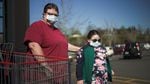 Two people wear face masks near a supermarket shopping cart.