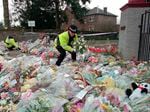A police officer arranges bouquets of flowers in rows at a side entrance to Dunblane Primary School following a school shooting that left 16 students and one teacher dead.