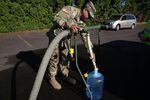 A National Guard soldier fills a container of water in the parking lot of a bowling alley in Salem.