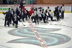 Seattle Kraken players kneel on the ice at their training facility as head coach Dave Hakstol outlines a play during NHL hockey practice, Thursday, Oct. 21, 2021, in Seattle. The Kraken will face the Vancouver Canucks, Saturday in Seattle for the expansion team's home opener. (AP Photo/Ted S. Warren)