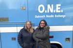 Two women stand in front of an ambulance converted into a mobile needle-exchange unit.