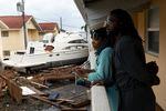 Frankie Romulus (left) and Kendrick Romulus stand on Sept. 29, 2022, outside their apartment in Fort Myers, Fla., next to a boat that floated into their complex when Hurricane Ian passed through the area.