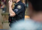 A Portland Police Bureau officer with his hand lifted towards his face.