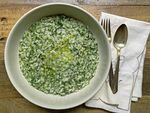 A bowl of risotto with small green pieces.