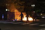 Police walk by a flaming dumpster during demonstrations in Portland, Ore., May 31, 2020. The protests ultimately ended with police using tear gas and rubber bullets to disperse the crowd gathered around the Justice Center in downtown Portland.