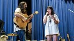 Linh Doan, right, sings her song for the Pass the Mic concert in Portland, Ore., Friday, Aug. 2, 2019. Sam Adams, left, of Portland band Sama Dams provides backing guitar.