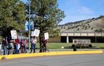 A cluster of people holding picket signs stand on a sidewalk near a building with a sign out front that reads "Oregon Institute of Technology."