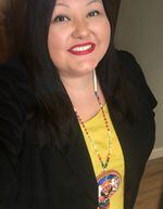 A smiling person wears a black blazer over a yellow shirt