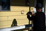 Antoinette Edwards takes a photo of bullet holes in an elderly couple's North Portland home on Jan. 30, 2019, in North Portland, Ore. 