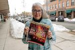Linda Navarre, a member of the Bonner County Human Rights Task Force, poses for a photo Monday, Feb. 7, 2022, in downtown Sandpoint, Idaho, as she holds a 1997 issue of Parade Magazine that contains an article mentioning the efforts of herself and others fighting against conservative extremist groups in northern Idaho.  Today, she says political divisions in the town are getting even wider, and a growing number of real estate companies seeking to capitalize on that trend are advertising that they can help people move out of liberal bastions like Seattle and San Francisco and find homes in places like rural Idaho.