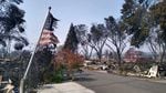 A partially burned American flag flutters in the breeze in front of the remains of a mobile home in Talent, Ore., on Thursday, Sept. 10. More than 50 mobile homes in this park were completely destroyed by the Almeda Fire, which came through the area Tuesday.