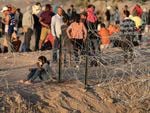 Immigrants wait near the U.S.-Mexico border fence this week in El Paso, Texas. The city has declared a state of emergency to access federal funding to house and feed the droves of new arrivals expected with the end of Title 42.