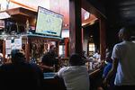 People gather around the bar while watching football.