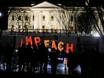 Protesters hold signs and sing in front of the White House on Dec. 17, 2019, the night before the House voted to approve articles of impeachment for former President Donald Trump.